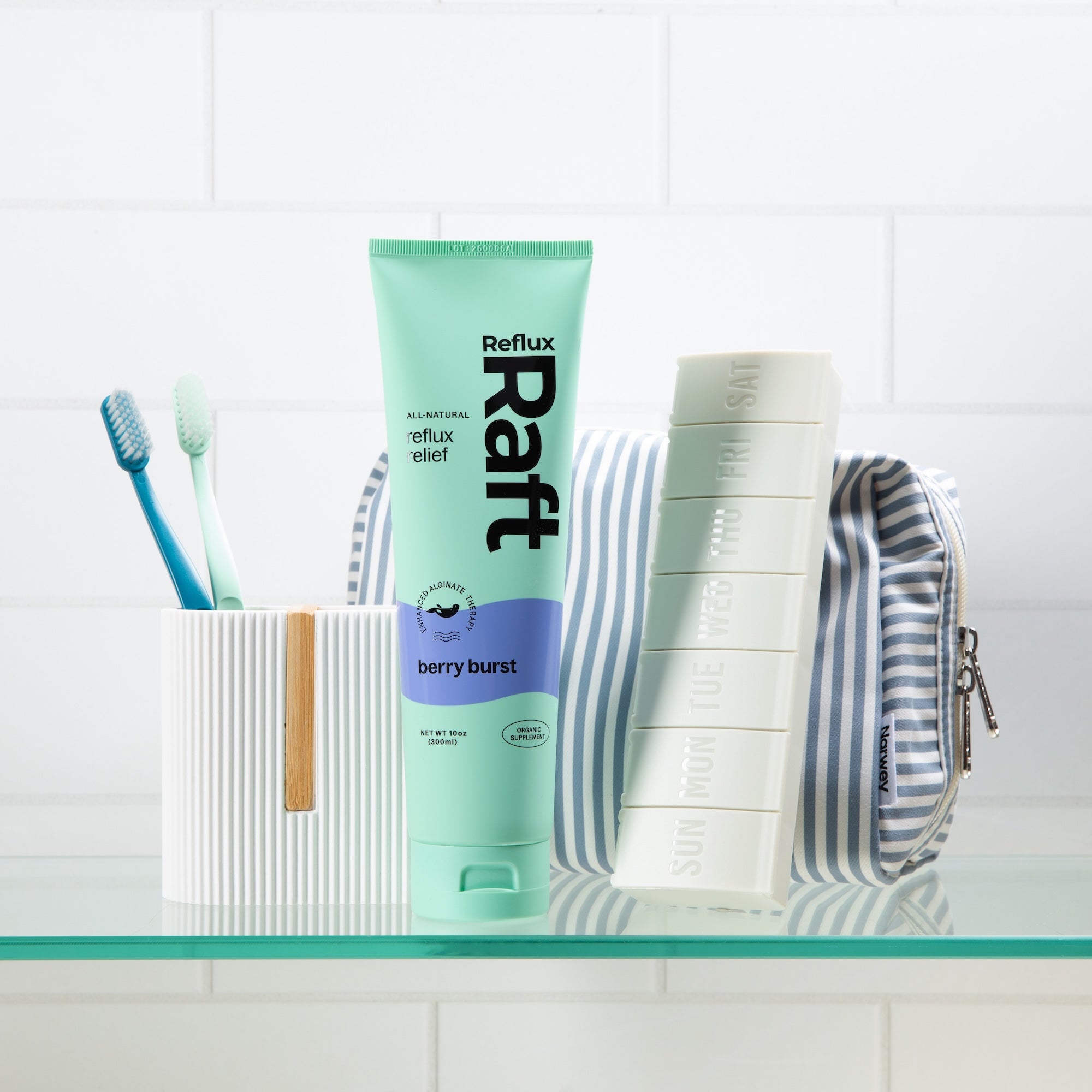 RefluxRaft Berry Burst alginate supplement tube displayed on a bathroom shelf with toothbrushes and a weekly pill organizer